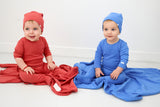 Two babies in deep pink and blue outfits embossed bear with matching hats on a white background